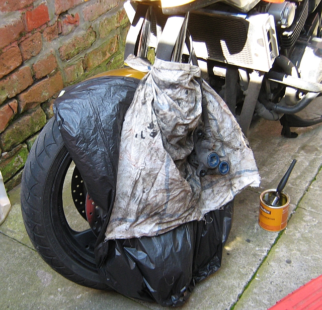 front wheel covered in plastic bag and rag to protect against brake fluid used for cleaning